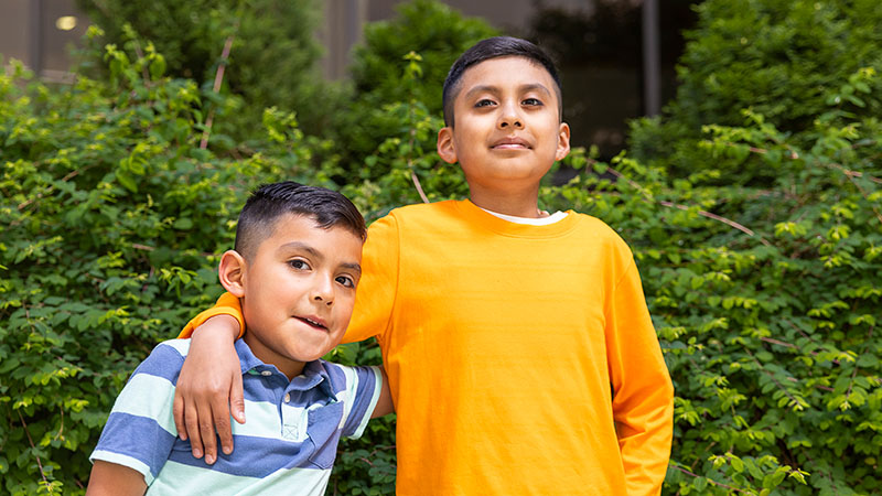 A boy and his little brother stand outside