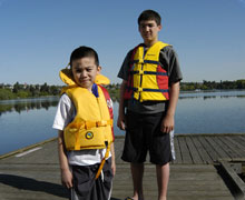 Kiddos standing on a dock with life jackets on