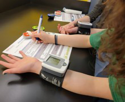 A student uses a blood pressure cuff.